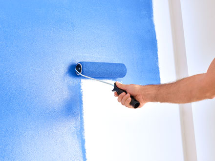 roller painting a wall blue